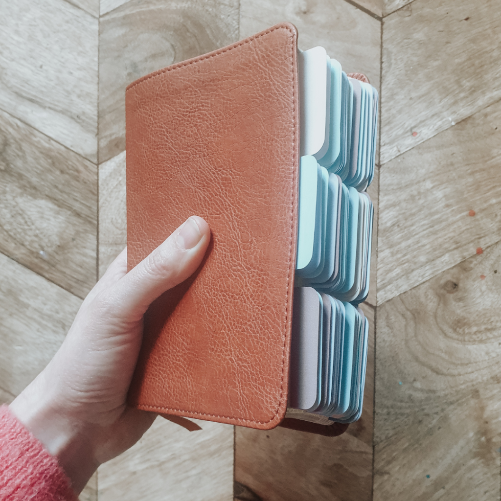 Woman holds a compact, tan leather bible in her hand with colourful tabs