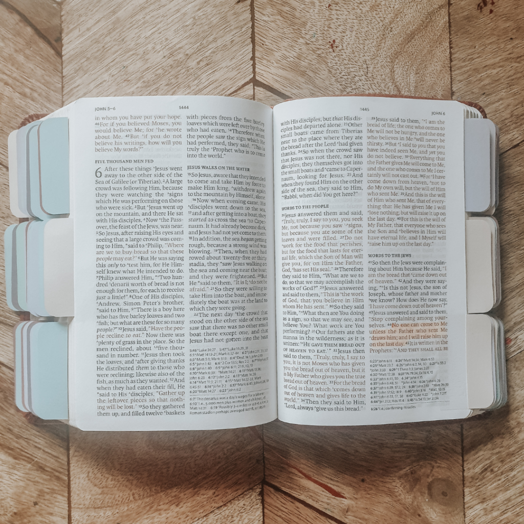 A bible is open on a table. Some text is highlighted and the pages are tabbed.